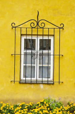 House window with a decorative protective grating. Yellow wall. clipart