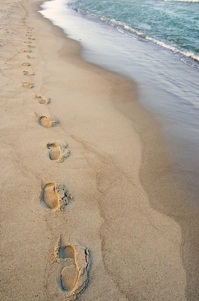 Huellas de los pies al lado de las olas alcanzando el margen. Paseo romántico . —  Fotos de Stock