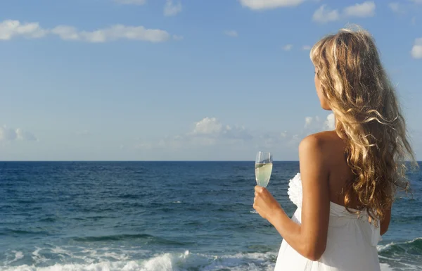 Красивая женщина в белом платье смотрит на море — стоковое фото