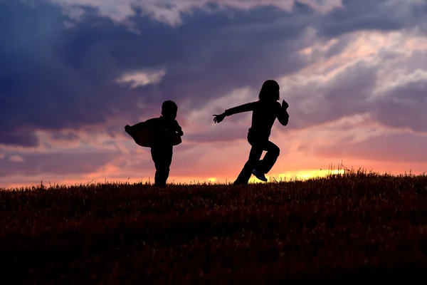 Діти біжать на заході сонця . — стокове фото