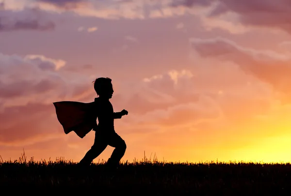 Chlapec hraje super hrdina při západu slunce. Stock Fotografie