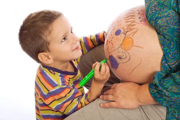 Lachende zoontje schilderij van de buik van zijn zwangere moeder — Stockfoto
