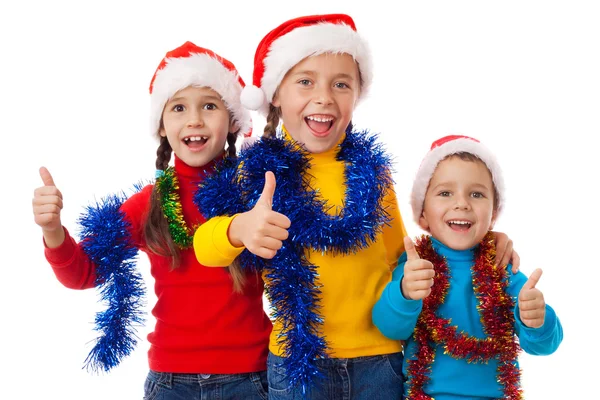 在圣诞老人的帽子与拇指向上标志中的三个孩子 — 图库照片