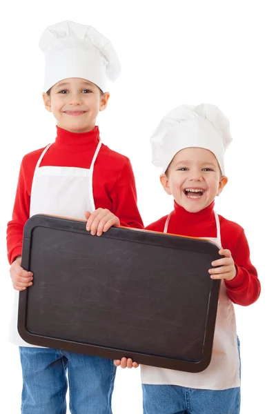 Smiling little cookers with empty chalkboard — Stock Photo, Image