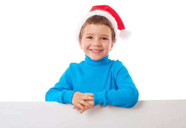 Garoto sorridente em chapéu de Papai Noel com banner vazio — Fotografia de Stock