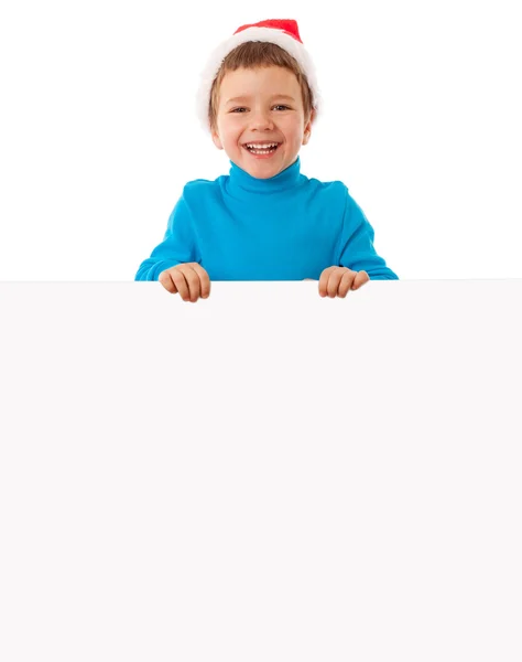 Smiling boy in Santa hat with empty banner — Stock Photo, Image