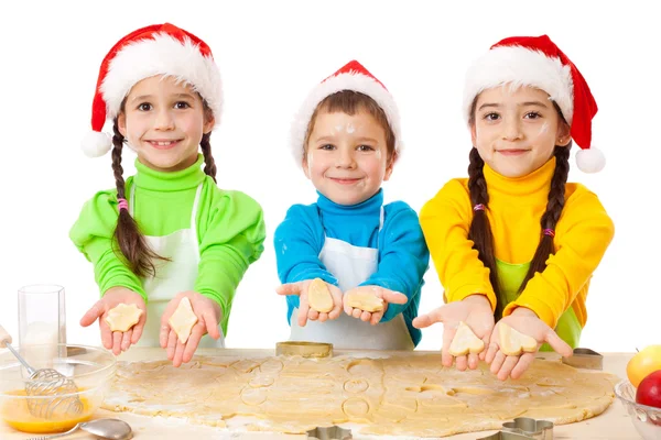Τρεις χαμογελαστά παιδιά που παρουσιάζουν Χριστούγεννα μαγείρεμα — Φωτογραφία Αρχείου