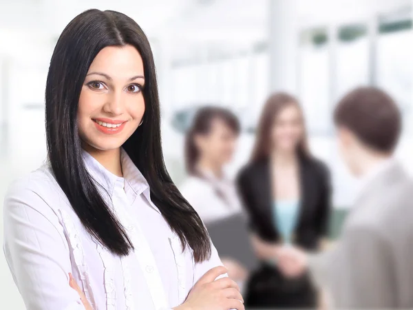 Успешная деловая женщина, стоящая со своим персоналом на заднем плане в офисе — стоковое фото