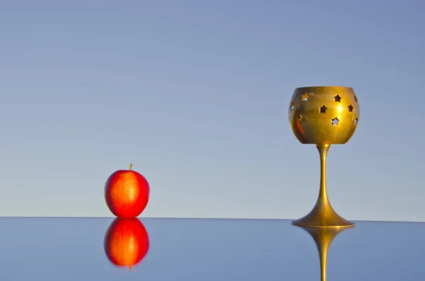 Red apple and brass candlestick — Stock Photo, Image