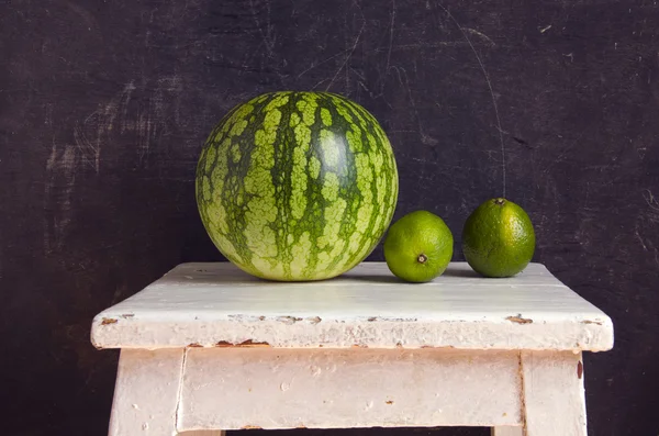 Watermelon and two green lemons — Stock Photo, Image
