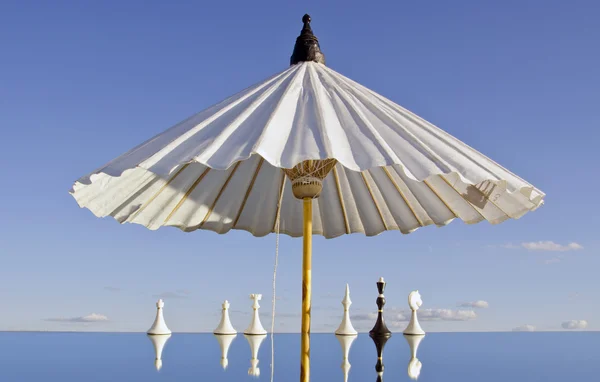 White umbrella and chessmans on mirror — Stockfoto