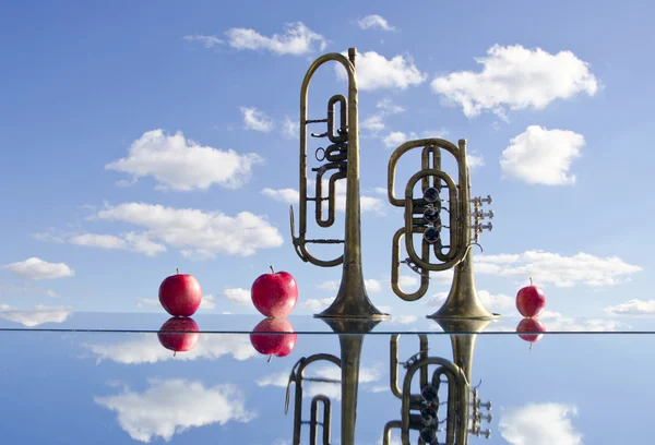 Brass instruments on mirror and apples — Stock Photo, Image