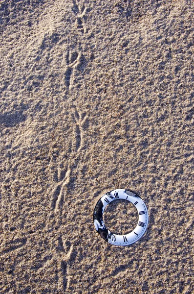 Vytiskne času symbol na písku a pták — Stock fotografie