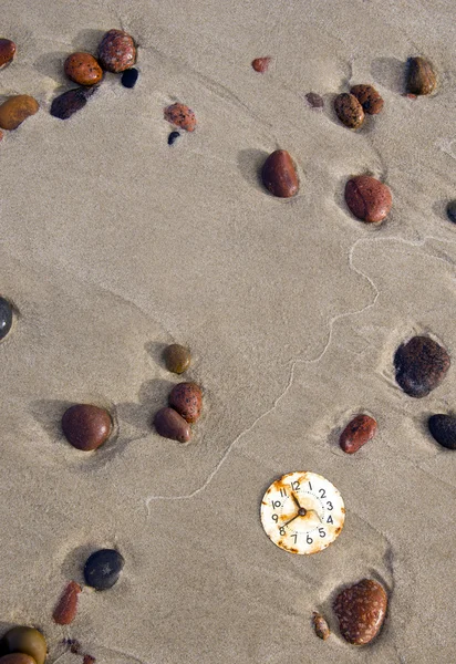Rusted clock dial on beach sand and stones — Stock Photo, Image