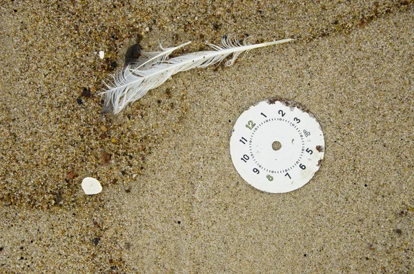 Clock face on beach sand and feather — Stock Photo, Image
