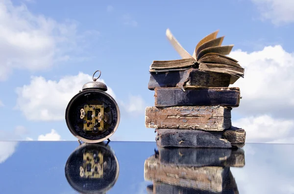 Винтажные книги и старые часы на зеркале — стоковое фото