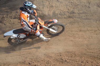Motocross rider on the motorcycle accelerates from turning clipart