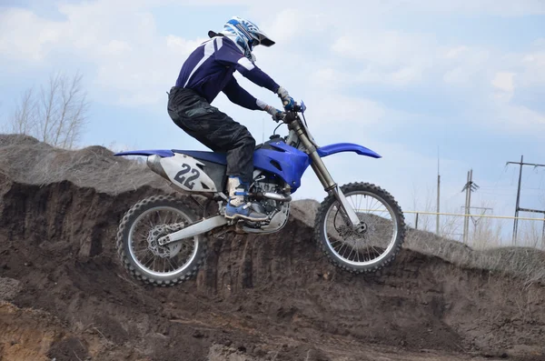 Motocross rider on the motorbike takes off on a high mound of ea — Stock Photo, Image