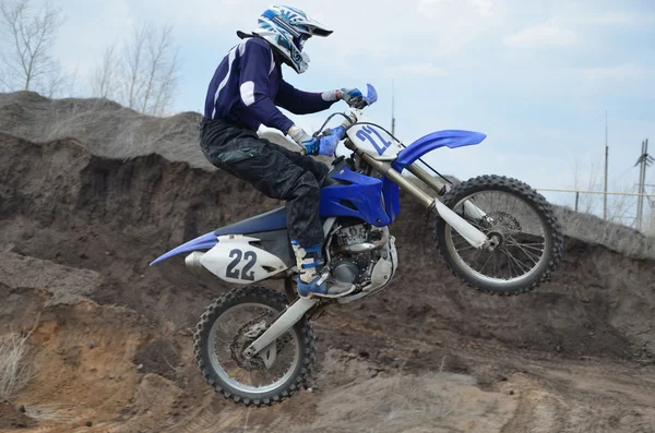 Motocross rider on the motorbike takes off on a high mound of ea — Stock Photo, Image