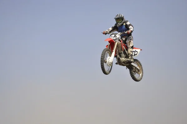 Jumps on a high mound of earth on the motorbike — Stock Photo, Image