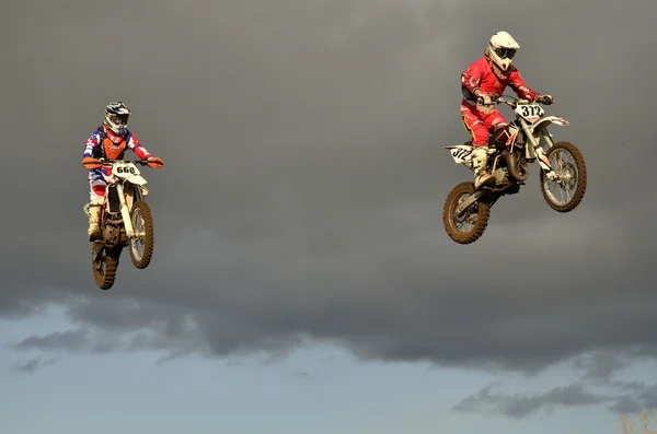 Літаючі дві гонки на мотоциклі проти — стокове фото