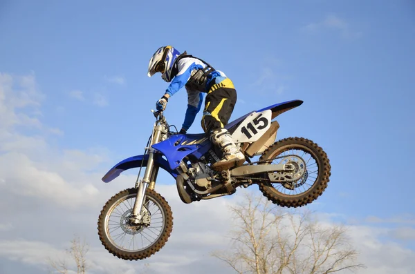 Motocross rider en una motocicleta volando a través de Imagen de stock