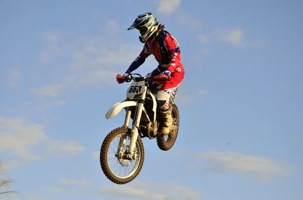Motocross rider flies through the air turning his head — Stock Photo, Image