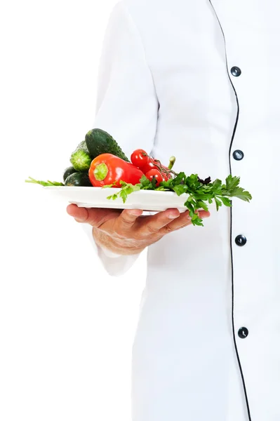 Повар держит тарелку с овощами — стоковое фото