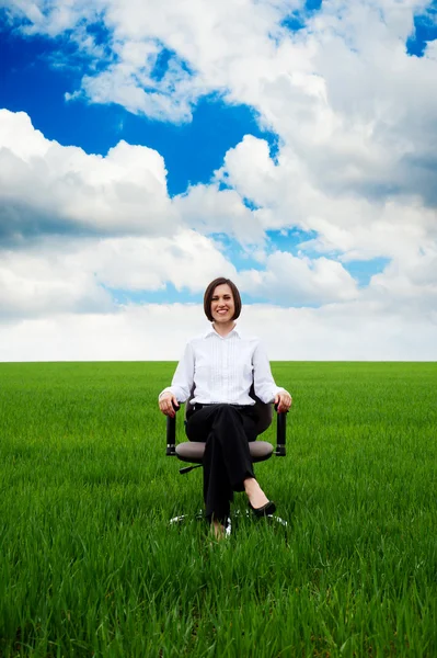 Kobieta siedzi na krześle przez zielone pola — Zdjęcie stockowe