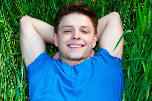 Yeşil alan üzerinde yatan genç adam — Stok fotoğraf
