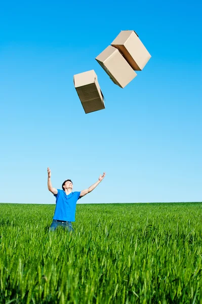 Man catching boxes on green field — Stock Photo, Image