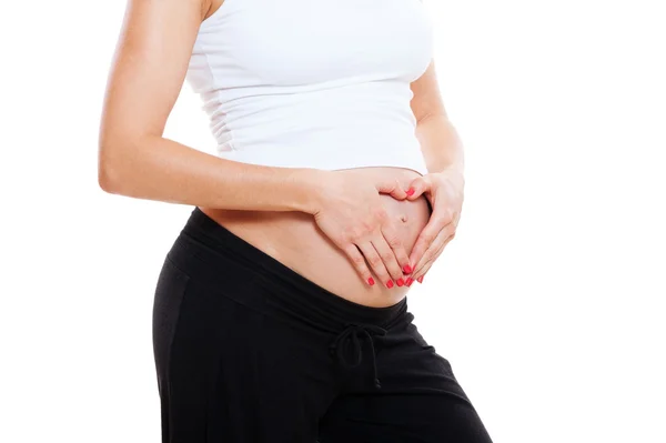 Vrouwelijke zwangere buik en handen als hart — Stockfoto