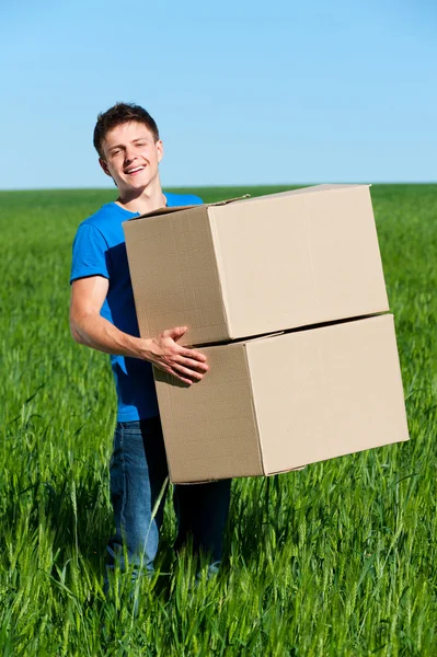 Man in blue t-shirt carrying boxes — Stock Photo, Image