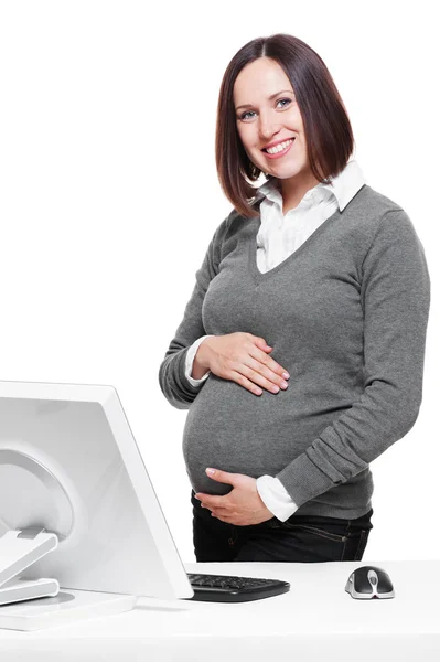Беременная женщина, стоящая рядом с рабочим местом — стоковое фото