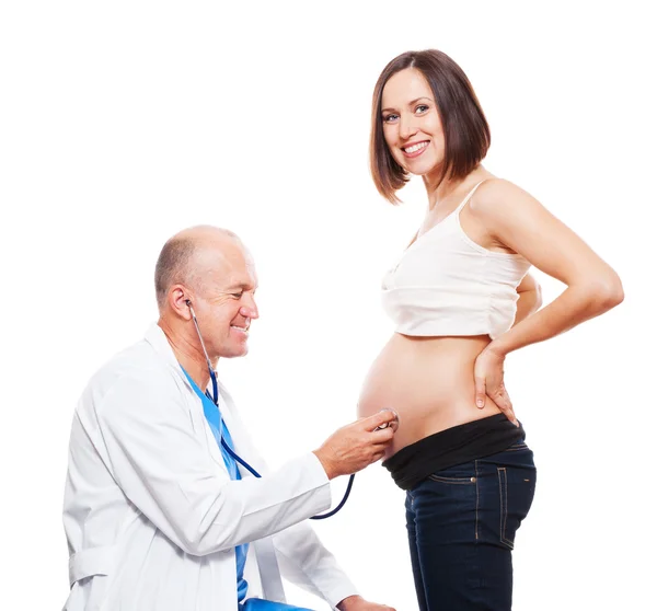 Médico sonriente escuchando el vientre de la mujer embarazada — Foto de Stock