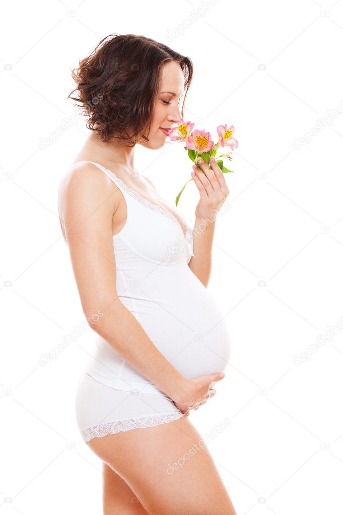 Pregnant woman in lingerie smelling flowers