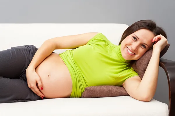 怀孕的女人在沙发上休息 — 图库照片