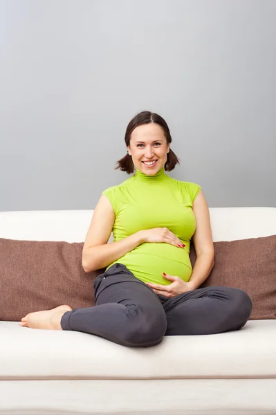 Mulher grávida sentada no sofá em casa — Fotografia de Stock