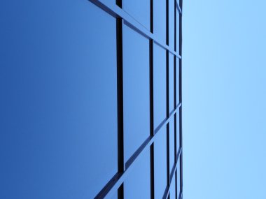 Blue square windows of office bulding in sharp angle, blue sky in top clipart