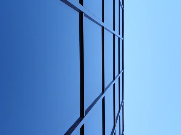 Blauwe vierkante ramen van office bulding in scherpe hoek, blauwe lucht in terug naar boven Stockfoto