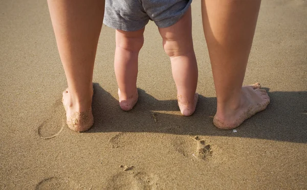 Mother and child walking on a sandy beach — Stock Photo, Image