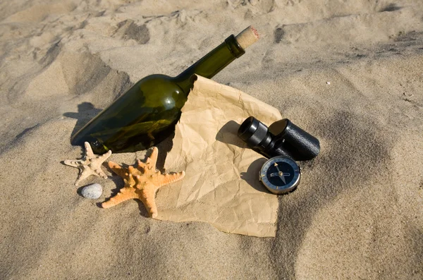 Vecchia carta, bussola, lavandino e bottiglia su fondo sabbia — Foto Stock