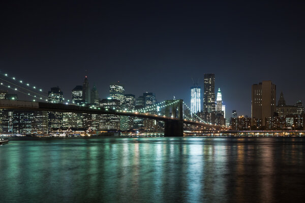 The New York City skyline at night w Brooklyn Bridge
