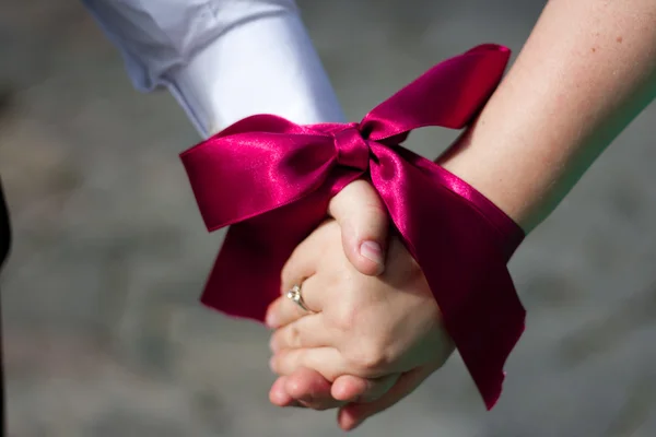 Ruce žen a mužů jsou spojeny s červenou stužku — Stock fotografie