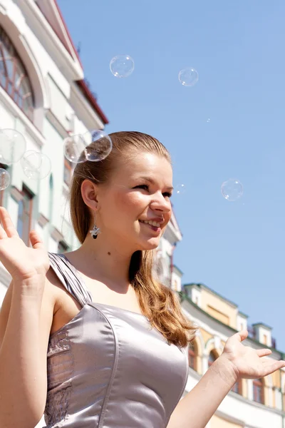 Hermosa chica con burbujas de jabón sobre un fondo del cielo — Foto de Stock