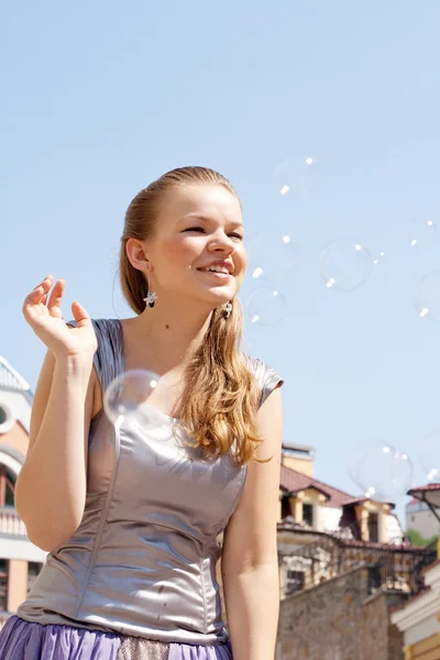 Hermosa chica con burbujas de jabón sobre un fondo del cielo — Foto de Stock