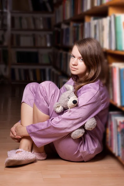 Flickan i rosa pyjamas i biblioteket — Stockfoto