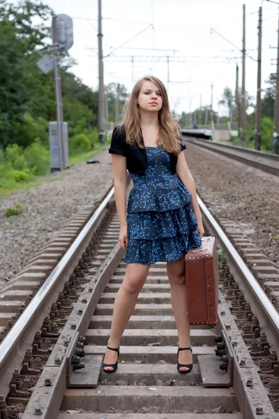 Девушка с чемоданом стоит на рельсах — стоковое фото