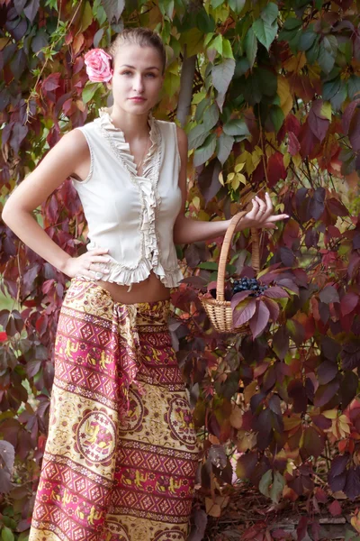 Menina bonita em uma saia longa com uma cesta de uvas — Fotografia de Stock