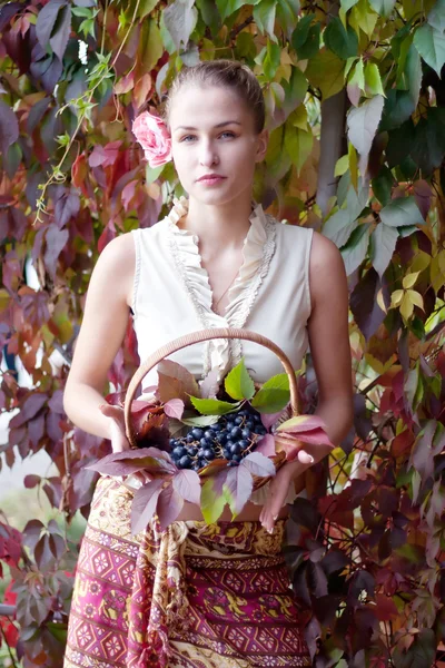 Vacker flicka i en lång kjol med en korg av druvor — Stockfoto